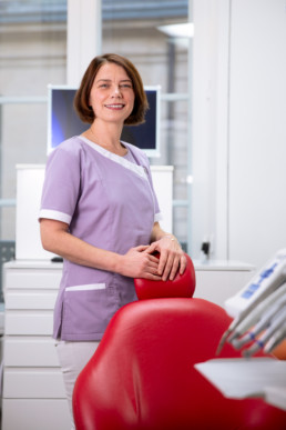portrait corporate du assistante dentaire avec une blouse mauve dans son cabinet dentaire